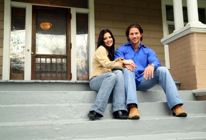Photo of a young couple in front of their Louisville home