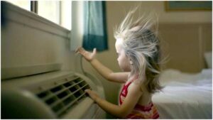 Photo of a young girl in front of an AC unit