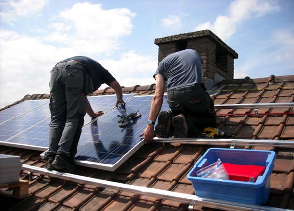 Photo of two workers installing solar panels on a roof