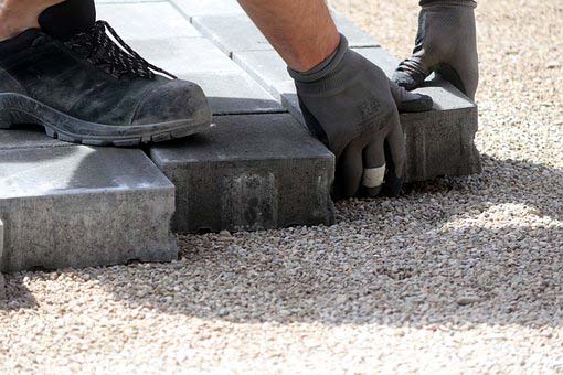 Photo of a man laying pavers for an outdoor patio