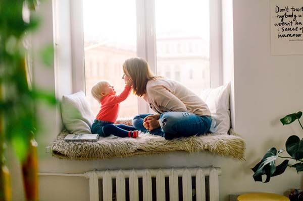 Photo of a mother with her child sitting in a window seat